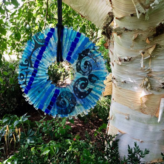 Blue glass disk hanging from a tree