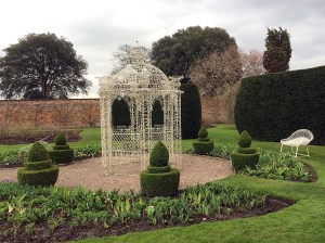 White wire gazebo in a formal garden with topiary