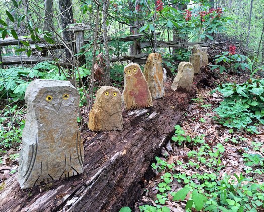 Eight stone owls with etched details and yellow eyes