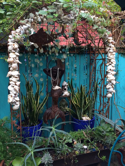 Container garden with mermaid under a shell arch