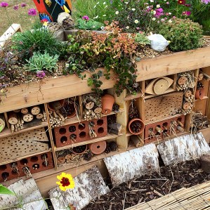 Bug hotel with bored wood, straw and flowerpots and bricks