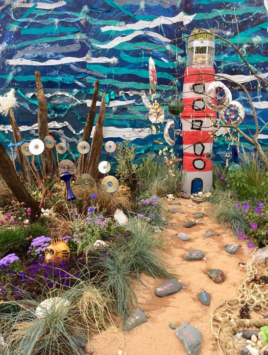 Sandy path leading to a lighthouse with coastal garden
