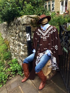 Scarecrow in blue jeans with a poncho, hat and cigar