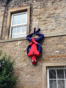Spiderman hanging from a web on the side of a house