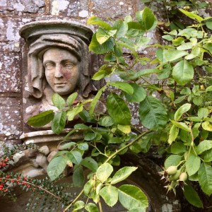 Stone carving of a veiled lady on a garden wall
