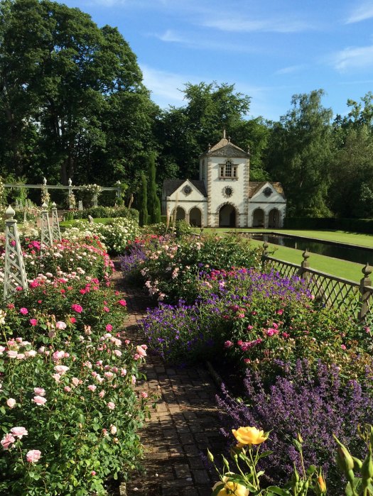 A folly behind a garden of roses and perennials