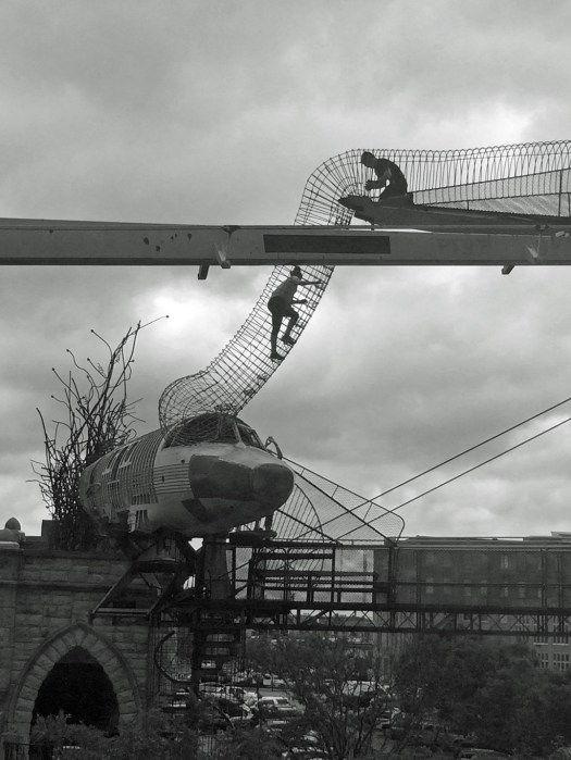 People helping each other up a giant slinky high up over a building