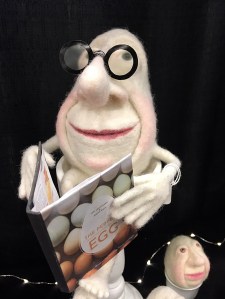 Felt character like an egg, holding a cookery book