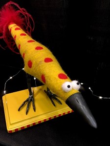 Yellow bird with polka dots standing on a plinth