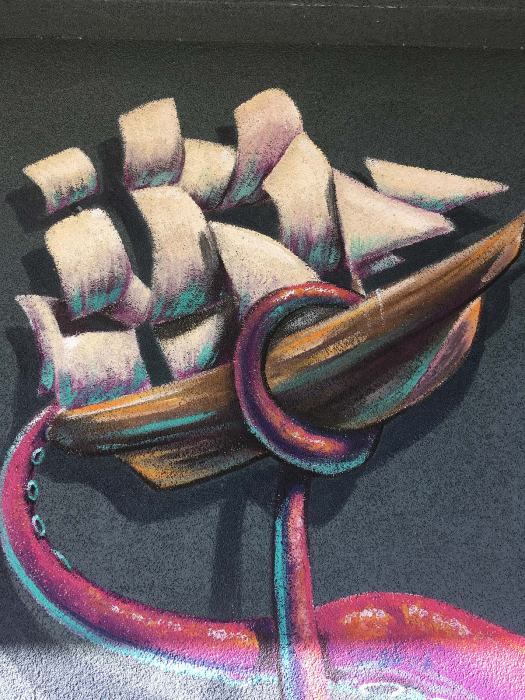 Street art of a giant cephalopod's tentacles lifting a sail boat