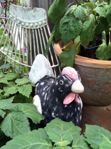 Pottery chicken with herbs and a rake