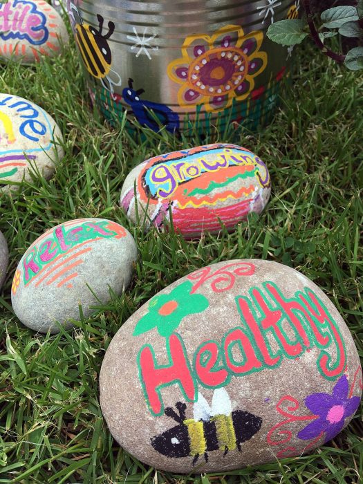 Pebbles painted with the words relax, growing, healthy