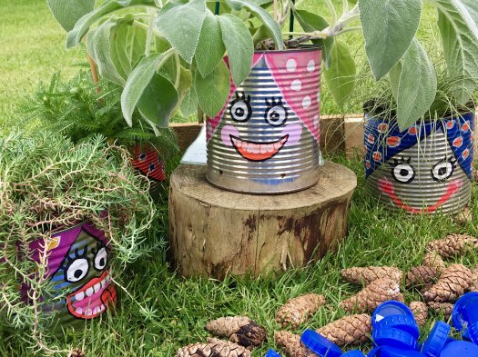 Recycled tin can plant pots with smiling faces painted on