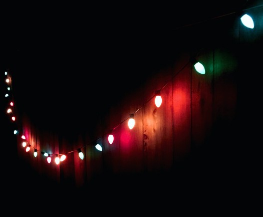 String lights reflect their colours on a fence