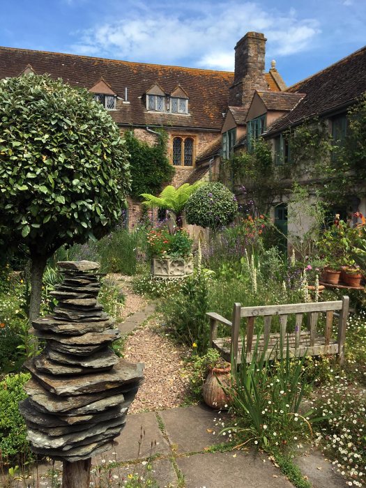 Path through topiary, rock stack, seating to Cothay Manor