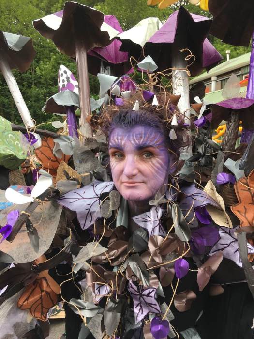 Performer with painted face and mushroom and vine costume