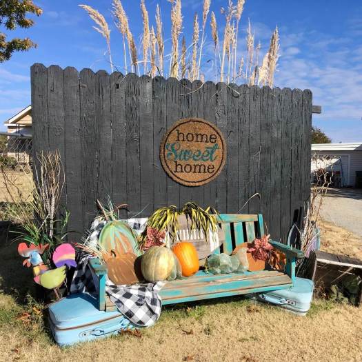 Bench propped up on suitcases with pumpkin art