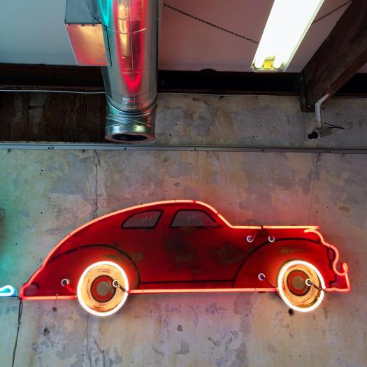 Red neon car hung on an old plaster wall