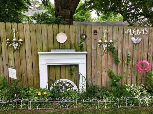 A fence with a white fireplace, light sconces and ornaments