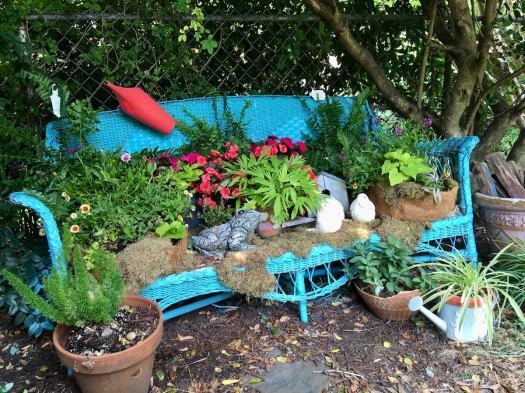 Turquoise wicker settee loaded with plants