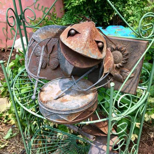 Metal drummer frog on a wire plant stand