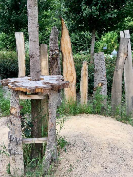 Natural wood fence with a ragged outline and a table around a sapling