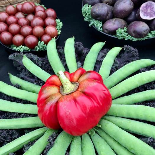 Pea pods arranged in a flower shape with purple potatoes and tomatoes