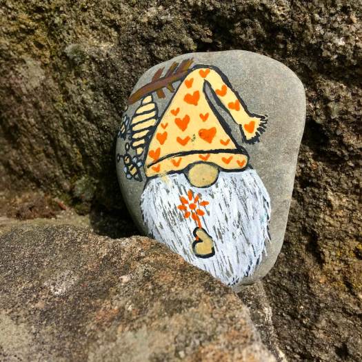 Cheerful gnome with bee and bee-hive on a pebble