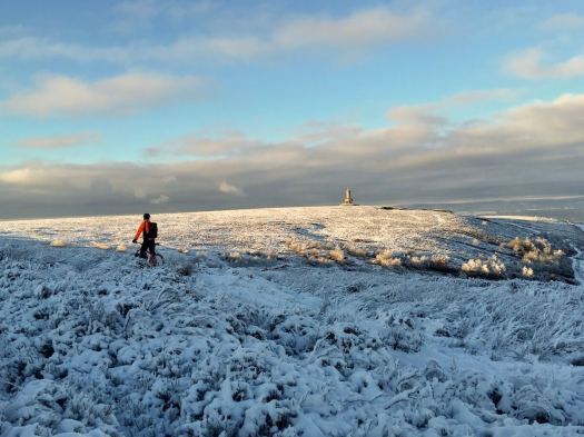 Cyclist looks towards Darwen tower in winter