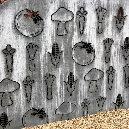 Outlines of tomatoes, mushrooms, leeks, carrots and corn cut into metal