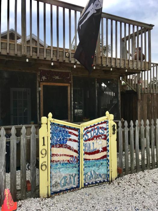 Simple picket fence with painted gate saying: Stars fall on Grayton Beach