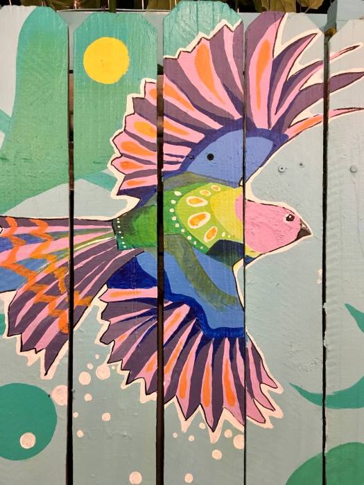 Fence with a painting of a colourful bird in flight
