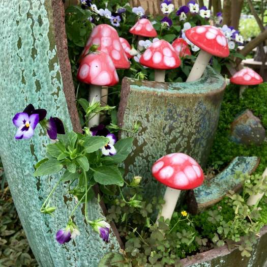 Broken planter with violas and glass red spotted toadstools