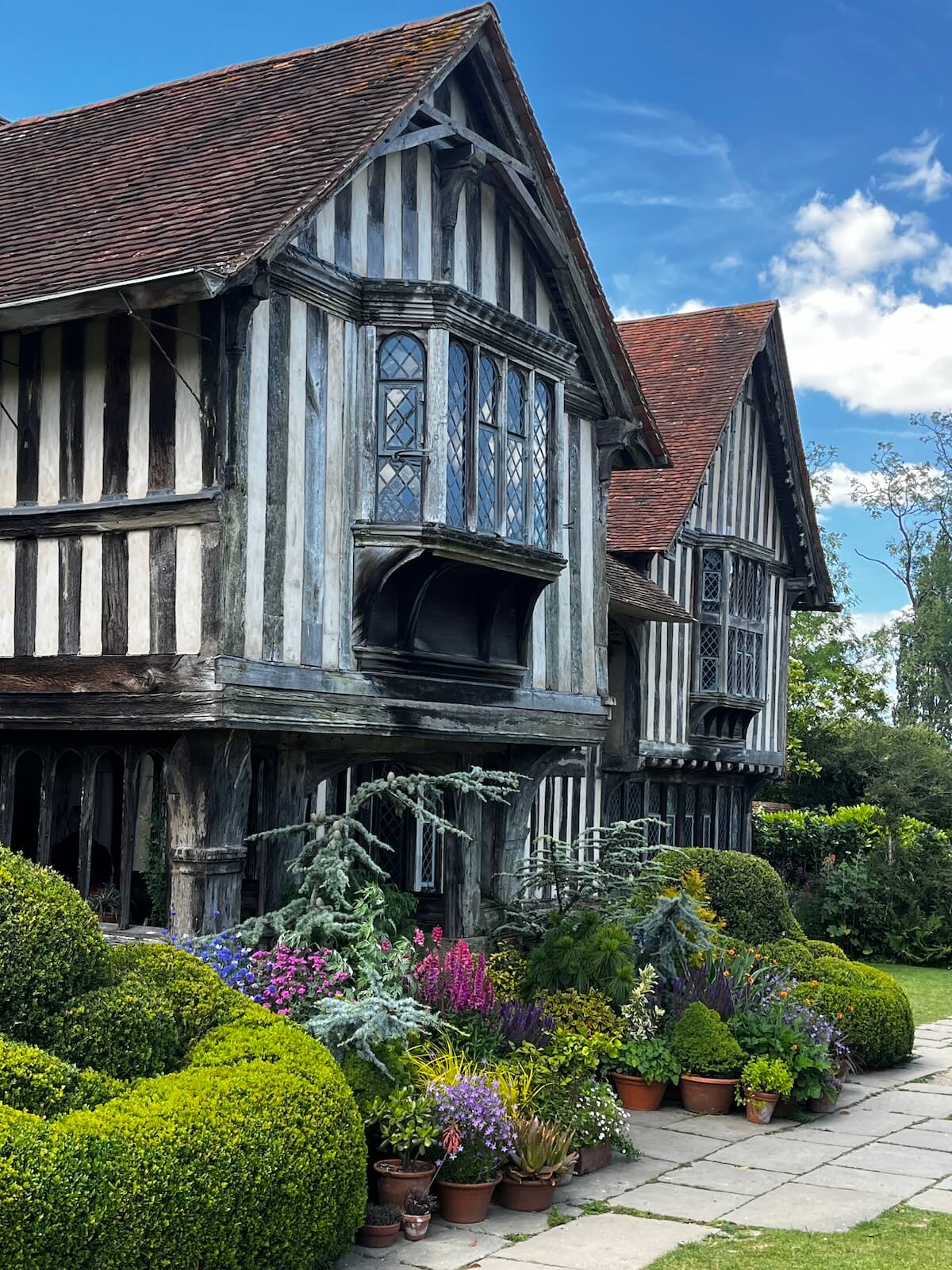 Great Dixter's front porch surrounded by a collection of potted plants