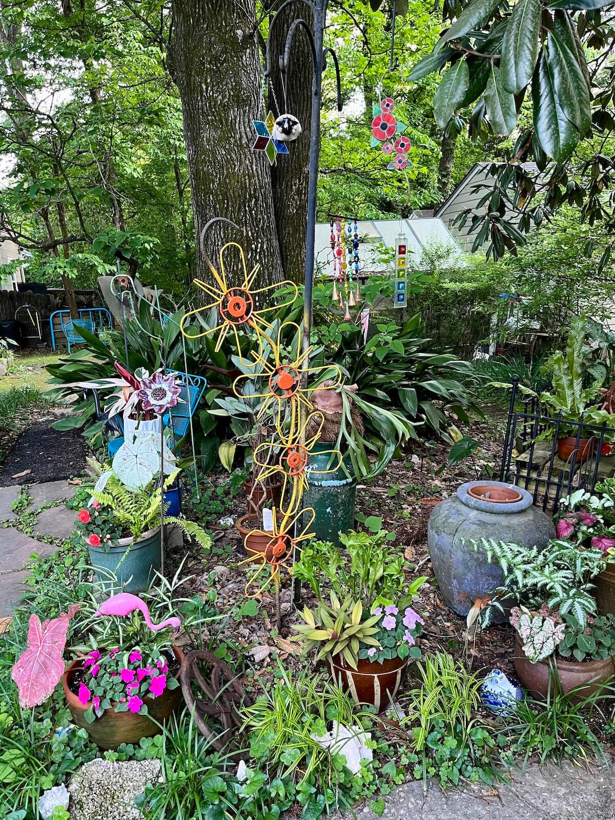 A shady garden with yard art and patchwork-style containerised plants