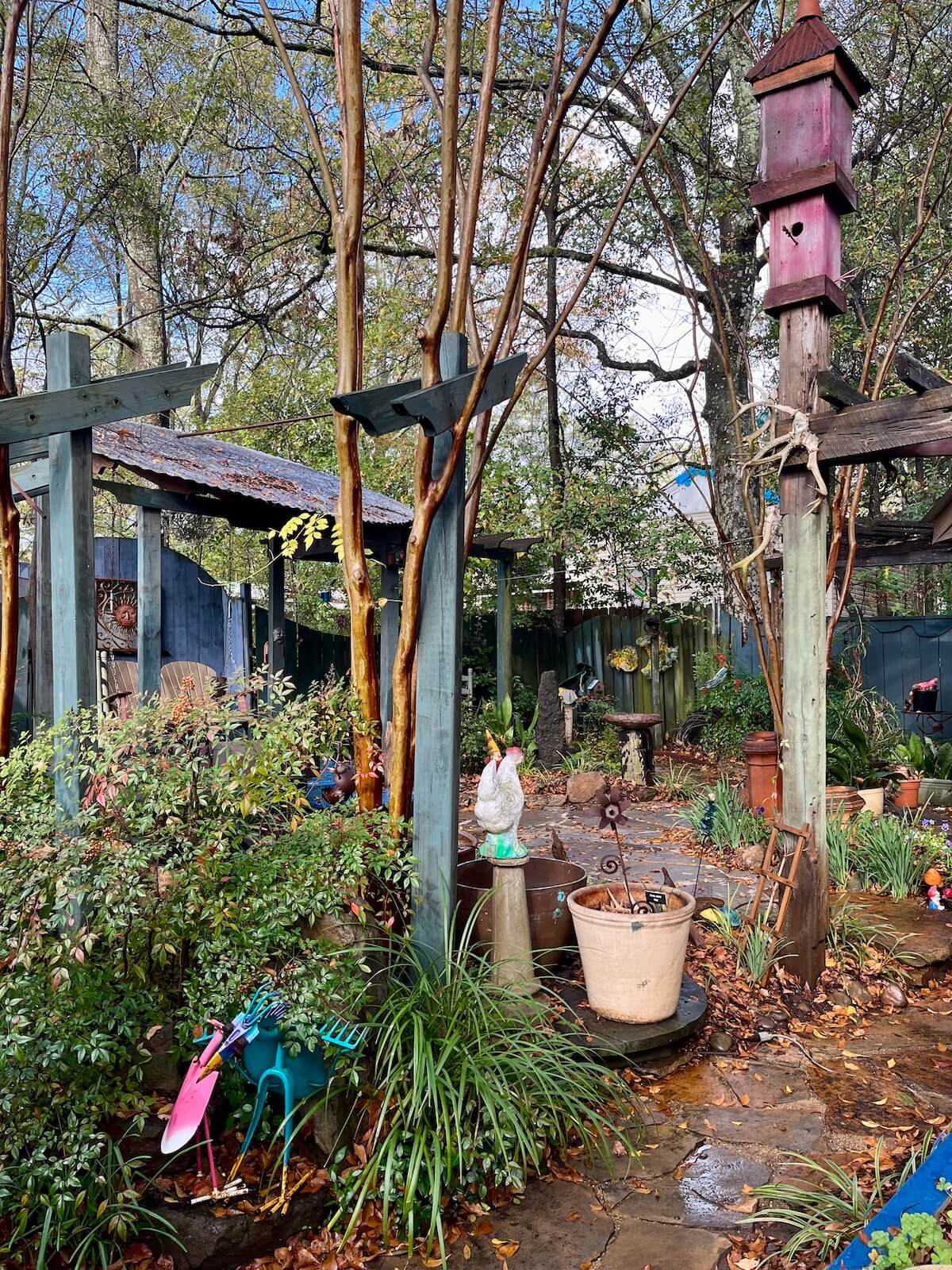 A garden with a pillars, a tall birdhouse and various pots