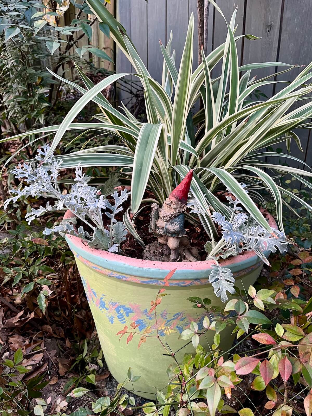 Greenish hand-painted pot with leafy plants and a gnome